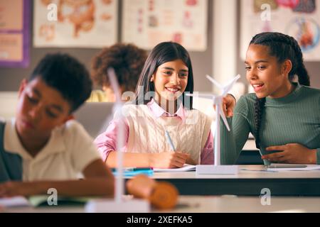 Secondary Or High School Students Studying Wind Turbines In Science Class With Teacher In Background Stock Photo