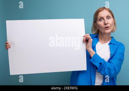 Middle age business concept. middle-aged woman holding a poster for notes with a mocap on a blue background copy space Stock Photo