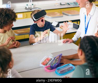 Amazed Male Secondary Or High School Pupil Wearing VR Headset In Science Class With Female Teacher Stock Photo