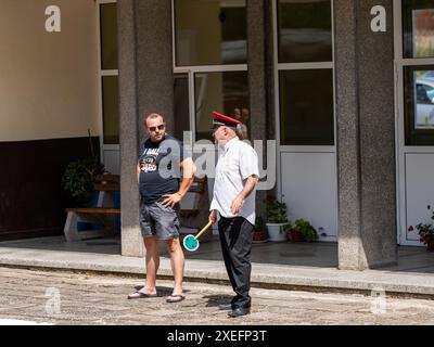 Two men having a discussion outside of a building on a bright sunny day Stock Photo