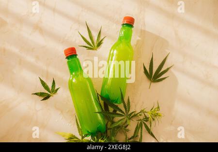 Two plastic juice bottles on a marble table with cannabis leaves. Stock Photo