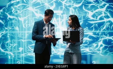 Teamworking colleagues using AI neural networks modeled after human brain to solve complex problems. Team of IT specialists using deep learning to look at data and complete tasks, camera A Stock Photo