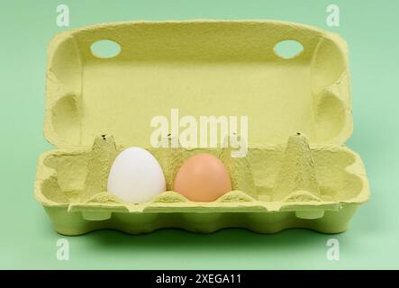 Two chicken eggs in a paper box on a green background Stock Photo