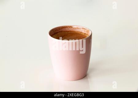 Pink coffee mug with cappuccino or latte with foam isolated on white background. Close-up Stock Photo