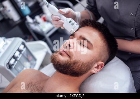 Closeup of face of beautiful relaxing man undergoing hardware cosmetology procedure in spa Stock Photo