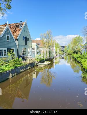 A peaceful river flows through a charming small town in the Netherlands, surrounded by traditional houses on either side Stock Photo