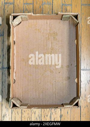 Empty dirty open cardboard box on a wooden floor Stock Photo