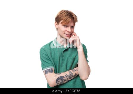 A young european man with red hair and a stylish hairstyle is dressed in a summer green collared t-shirt Stock Photo