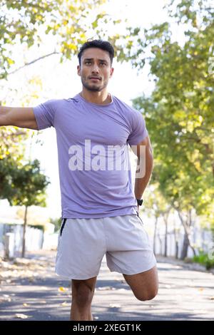 Stretching outdoors, man in athletic wear preparing for run in park Stock Photo