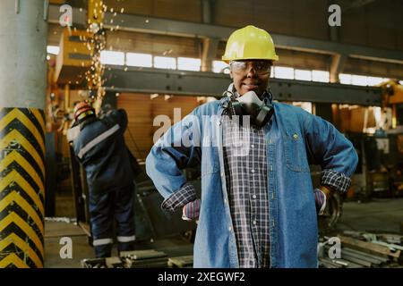 Medium portrait of self-confident African American woman in workwear posing for camera at workplace in modern factory Stock Photo