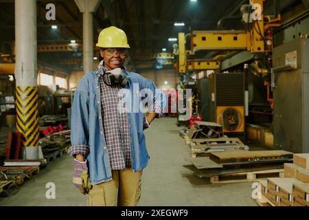 Medium long portrait of self-confident young African American female technician posing for camera at work in factory, copy space Stock Photo