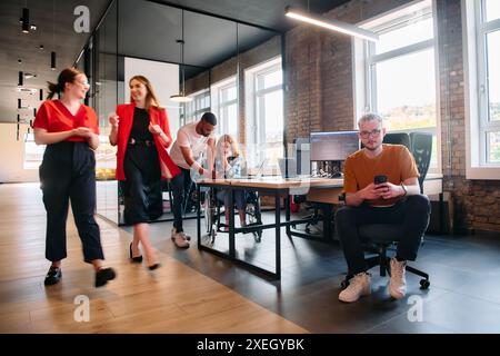 A diverse group of business professionals collaborates in a modern startup coworking center, utilizing a mix of paper-based and Stock Photo