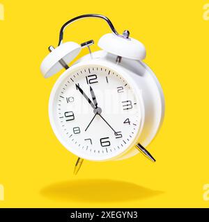 White bell alarm clock hovering over yellow background. 5 to 12 clock concept isolated Stock Photo