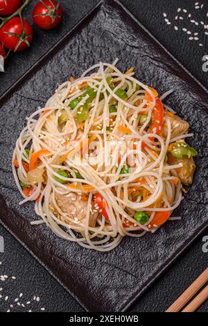 Tasty dish of Asian cuisine with rice noodles, chicken, asparagus, pepper, sesame seeds Stock Photo