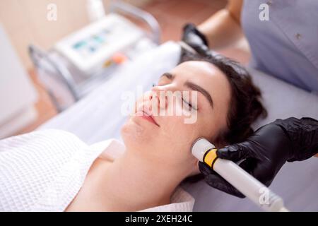 Closeup of face of beautiful relaxing girl undergoing hardware cosmetology procedure in spa Stock Photo