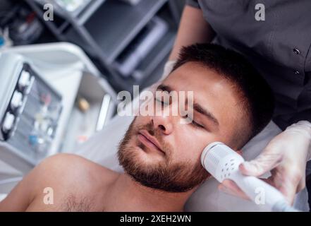 Closeup of face of beautiful relaxing man undergoing hardware cosmetology procedure in spa Stock Photo