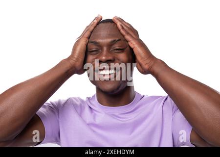 Young excited american man with short haircut wearing lilac t-shirt holding his head Stock Photo