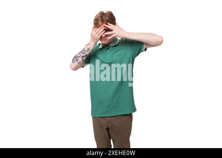 Young handsome caucasian red-haired man dressed in a green t-shirt has doubts and ponders Stock Photo