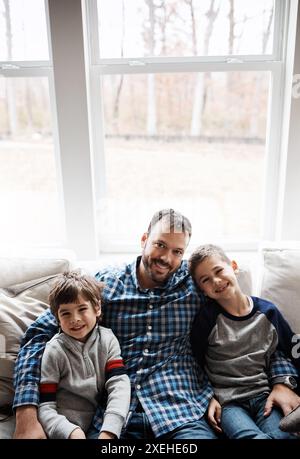Boys, father and hug portrait in home, support and together for bonding in lounge. Children, sons and daddy in embrace for security in connection Stock Photo