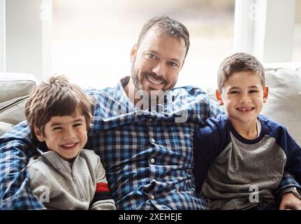 Boys, father and hug portrait in living room, support and together for bonding in home. Children, sons and daddy in embrace for security in connection Stock Photo