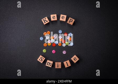 A concept consisting of the inscription of the word smile, with round emoticons on a dark concrete background Stock Photo