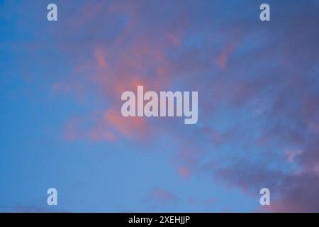 Dramatic sunset or sunrise scene. Pink and purple summer clouds against blue sky Stock Photo