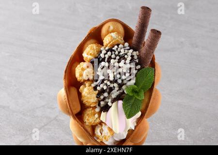 Trendy Hong Kong bubble waffles with ice cream, cream and berries on white wooden background. Copy space Stock Photo