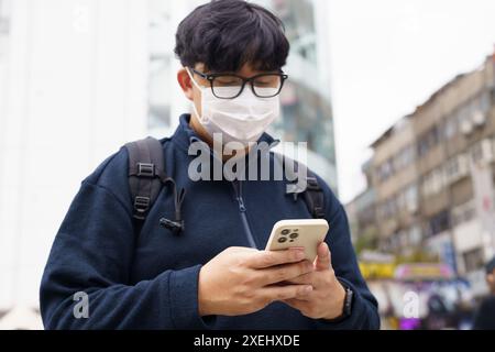 Man in downtown city street ordering taxi using smart phone app Booking taxi using application online on smart phone Stock Photo