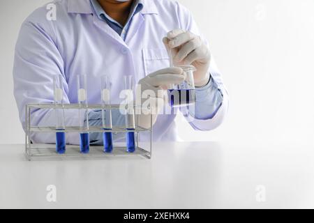 Science innovative Male medical or scientific laboratory researcher performs tests with blue liquid in laboratory. equipment sci Stock Photo