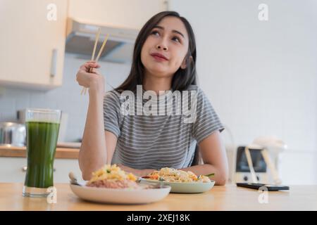 Asian Girl Â eating Thai food in kitchen counter Home delivery food feeling happyÂ Stock Photo