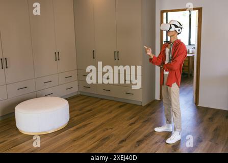 Using VR headset, young man exploring virtual environment in modern home setting Stock Photo