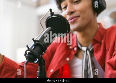 Recording podcast, young man wearing headphones speaking into microphone Stock Photo