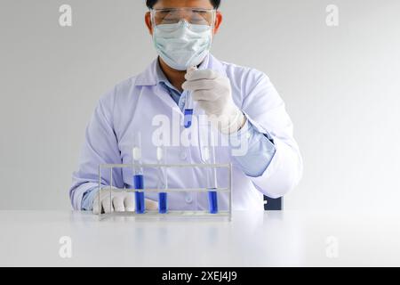 Science innovative Male medical or scientific laboratory researcher performs tests with blue liquid in laboratory. equipment sci Stock Photo