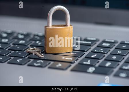Close-up of closed lock with key on computer keyboard Stock Photo