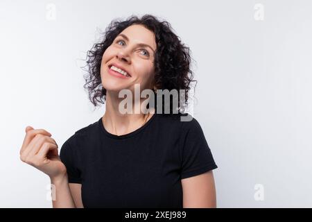 Dreamy brunette with curly hairstyle against a copy space background, studio shot Stock Photo
