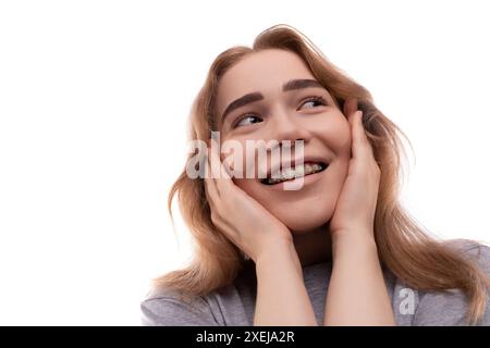 Modest teenage girl with blond hair and braces on a white background Stock Photo