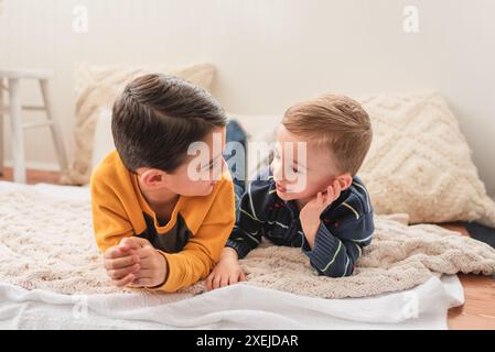 Two smiling brothers lying on a blanket and talking Stock Photo