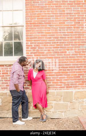 Couple looking at each other leaning against brick wall Stock Photo