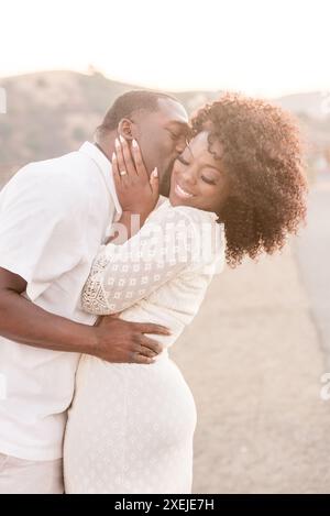Man holding woman and giving her a kiss on the cheek, woman afro Stock Photo