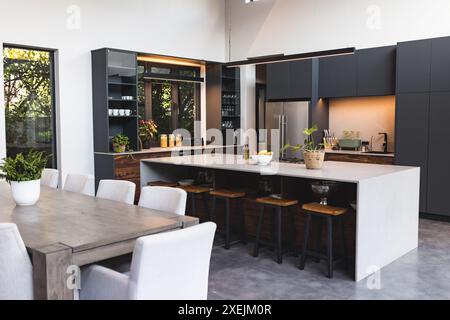 Modern kitchen with large island, bar stools, and dining table in contemporary home Stock Photo