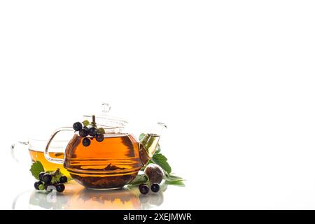 herbal tea from currant leaves and berries in a cup and in a teapot, isolated on white background Stock Photo