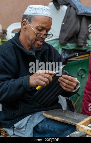 Traditional shoemaker in the souk of the Marrakesh medina repairing old shoes Stock Photo