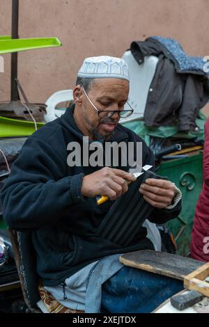 Traditional shoemaker in the souk of the Marrakesh medina repairing old shoes Stock Photo