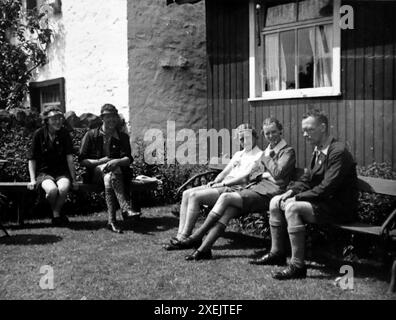 Relaxing on benches in Gisburn, a village in the Ribble Valley, Lancashire. Cycling tour, 1937. From an album which covered a journey by bicycle in the UK by a group of enthusiastic cyclists. The album was compiled and annotated by an amateur photographer and the tour included North Wales, Yorkshire, Lancashire and Cumbria. There was no indication of who compiled the album. Original photograph sizes varied, the smallest being about 3x2 inches, the largest about 7x5. Stock Photo