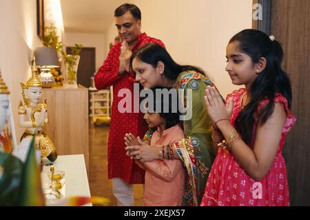 Indian Family Praying Together At Home Stock Photo