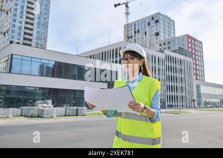 Industrial worker female builder with working documents, outdoor construction Stock Photo