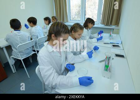 At the school chemistry lab, chemistry lesson. Pupils in lab coats taking samples using Petri dishes and tweezers. November 29, 2018. Kyiv, Ukraine. Stock Photo