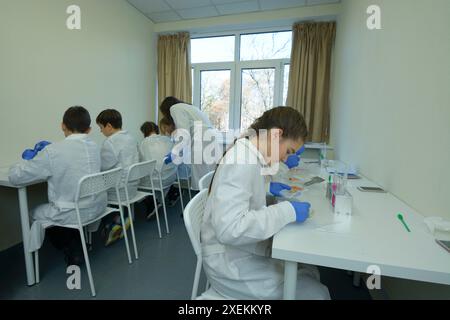 At the school chemistry lab, chemistry lesson. Pupils in lab coats taking samples using Petri dishes and tweezers. November 29, 2018. Kyiv, Ukraine. Stock Photo