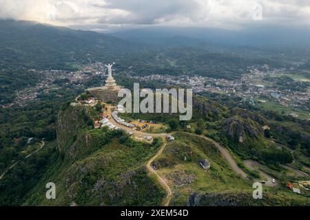 Aerial view of the Jesus Christ Blessing Statue and city in the valley under a cloudy sky; Makale, Tana Toraja Regency, South Sulawesi, Indonesia Stock Photo