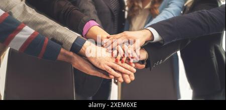 Business team putting hands together in unity - concept of teamwork and collaboration, corporate team building, diverse office environment, working to Stock Photo